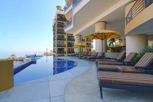 a resort with a pool and chairs and an umbrella at Pinnacle Resort-Style Condo - Luxurious Balcony in Puerto Vallarta