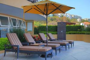 a group of chairs and an umbrella on a patio at Pinnacle Resort-Style Condo - Luxurious Balcony in Puerto Vallarta
