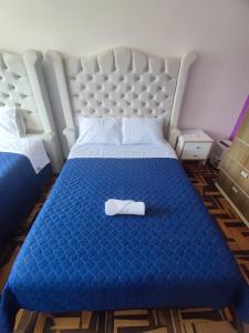 a blue bed with a towel on it in a room at SUMAQ PUÑUY HOSTEL - LIMA AIRPORT in Lima
