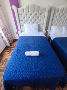 Una habitación de hotel con una cama azul con una toalla. en SUMAQ PUÑUY HOSTEL - LIMA AIRPORT, en Lima