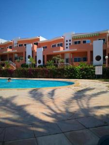 a swimming pool in front of a large building at Oasis en bord de mer - Appartement avec piscine in Imi Ouaddar