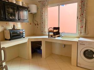 a kitchen with a counter with a microwave and a sink at Oasis en bord de mer - Appartement avec piscine in Imi Ouaddar