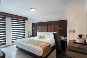 ein Hotelzimmer mit einem großen Bett und einem Schreibtisch in der Unterkunft Sleep Inn Puebla Centro Hist rico in Puebla