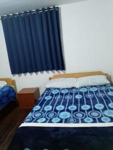 1 cama en un dormitorio con cortina azul en Black Sheep Hostel Cusco, en Cusco