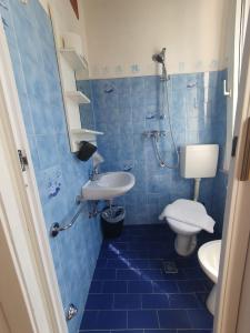La salle de bains est pourvue de carrelage bleu, d'un lavabo et de toilettes. dans l'établissement HOTEL IDEALE young people under 40, à Rimini