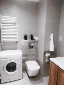 a bathroom with a washing machine and a toilet at Apartament Bażantów in Katowice