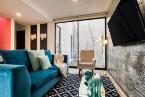 een woonkamer met een blauwe bank en een tv bij MEDELLIN by Mr W in Mexico-Stad +168 foto's