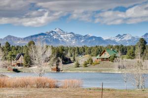 a house and a lake with mountains in the background at Lakefront Pagosa Springs Escape Near Hiking Trails in Pagosa Springs