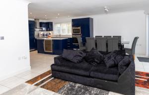 a living room with a black couch and a kitchen at Supreme Class Properties in Eastchurch