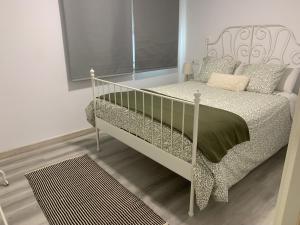 een wit bed in een witte kamer met een nachtrok bij Picolo in Cee