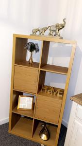 a wooden bookcase with shelves and a vase on top at City Centre Flat with Free Parking in Newport