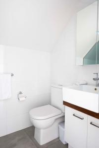 La salle de bains blanche est pourvue de toilettes et d'un lavabo. dans l'établissement Sunlit Serenity in the Heart of Collingwood, à Melbourne