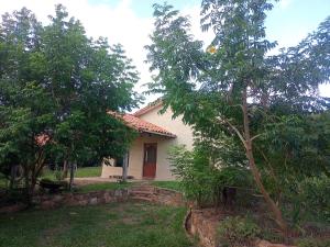 una piccola casa bianca con degli alberi di fronte di Casa Loto a Samaipata
