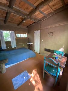 Schlafzimmer mit einem blauen Bett und einem Tisch in der Unterkunft Eco habitación en Tierra Fértil Eco Posada in Santa Ana