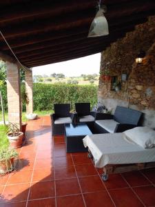 eine Terrasse mit Sofas, Tischen und einer Steinmauer in der Unterkunft C M Casa de Mares Alojamento Local in Casas Novas de Marés