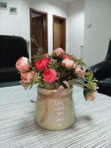 un jarrón lleno de flores rosas en una mesa en Apartman Mladenovic Center, free parking&wifi en Vranje