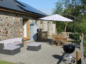 a patio with a grill and an umbrella at 2 Bed in Aberystwyth 83552 in Llanilar