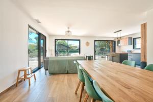 una sala de estar con una gran mesa de madera y sillas verdes. en Peaceful house on the edge of a forest, en Sanguinet