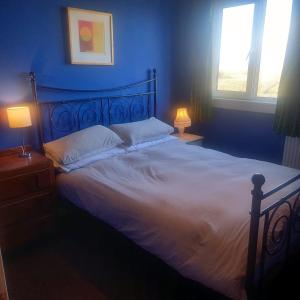 1 dormitorio con 1 cama grande con sábanas blancas y 2 lámparas en Comfortable detached 4 bedroomed holiday home, en Balivanich