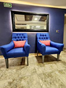 2 sillas azules y un espejo en una habitación en Hotel Roque en Torreón
