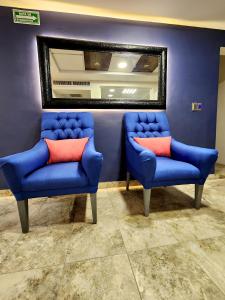 two blue chairs and a mirror in a room at Hotel Roque in Torreón