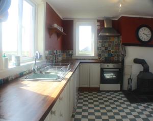 a kitchen with a sink and a clock on the wall at Comfortable detached 4 bedroomed holiday home in Balivanich