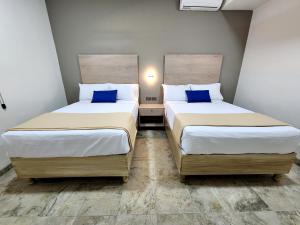 トレオンにあるHotel Roqueの小さな部屋に青い枕が置かれたベッドが2つ