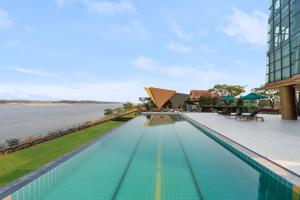 einen Pool mit Blick auf das Wasser und ein Gebäude in der Unterkunft Naka-Raj Escape Hotel in Nakhon Phanom