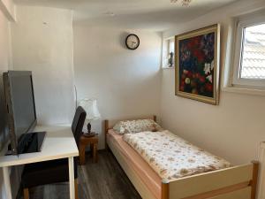 ein Schlafzimmer mit einem Bett, einem Schreibtisch und einer Uhr in der Unterkunft Gästehaus Linden - Zweibettzimmer in Linden