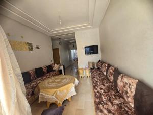 een woonkamer met een bank en een tv bij Résidence Perla Andaloussia in Mansouria