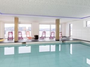 a swimming pool with red chairs in a room at Lärchenhof Top 302 in Mauterndorf