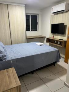 a bedroom with a blue bed and a flat screen tv at Apt Completo no West Flat in Mossoró