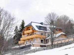 a large wooden house on top of a snow covered hill at Lärchenhof Top 302 in Mauterndorf