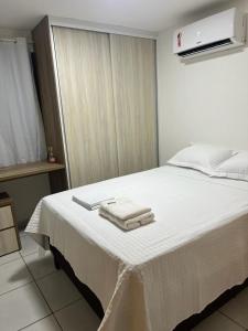 a bedroom with a white bed with towels on it at Apt Completo no West Flat in Mossoró