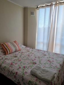 Un dormitorio con una cama con una manta de flores y una ventana en Ovalle Hotel Arauco, en Ovalle