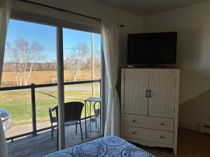 a bedroom with a television and a sliding glass door at Light House Apartment in Brackley Beach