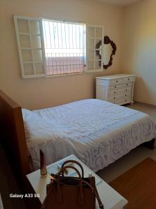 ein Schlafzimmer mit einem Bett, einer Kommode und einem Fenster in der Unterkunft TRANQUILIDADE- CHAPÉU DO SOL in São João da Barra
