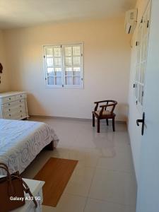 ein Schlafzimmer mit einem Bett, einem Stuhl und einem Fenster in der Unterkunft TRANQUILIDADE- CHAPÉU DO SOL in São João da Barra