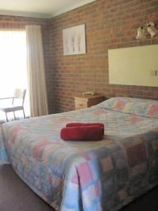 um quarto com uma cama grande e uma parede de tijolos em Barham Colonial Motel em Barham
