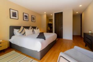 a bedroom with a large white bed and a couch at Capitalia Galileo Residences in Mexico City +41 photos