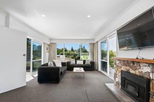 Una sala de estar con chimenea y televisión. en Te Moenga Treasure - Acacia Bay, en Taupo