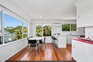 Una cocina con gabinetes blancos y una mesa y sillas. en Te Moenga Treasure - Acacia Bay, en Taupo