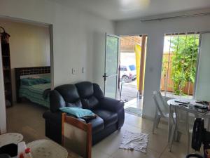 a living room with a chair and a bedroom at CASA JARDIM PINHEIROS in Maceió