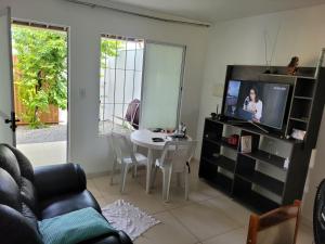 ein Wohnzimmer mit einem TV und einem Esstisch in der Unterkunft CASA JARDIM PINHEIROS in Maceió