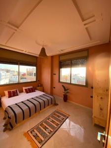 a bedroom with two beds and a rug at Adrenalin Surf House in Tamraght Ouzdar