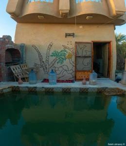 a house with a painting on the wall next to a swimming pool at غزاله كامب in Siwa