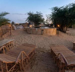 a group of wooden tables and chairs in the sand at غزاله كامب in Siwa