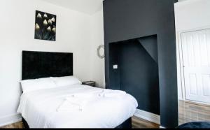 ケンブリッジにあるCambridge House Hotelの黒のアクセントの壁の白いベッドが備わるベッドルーム1室