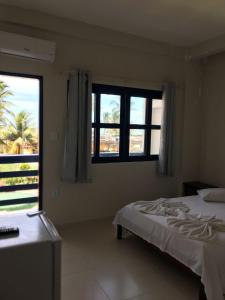 a bedroom with a bed and two windows at Recanto do Hibisco in Prado