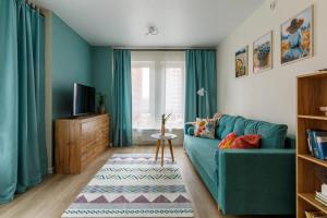 Современные Апартаменты с 2 комнатами : غرفة معيشة بها أريكة زرقاء وتلفزيون